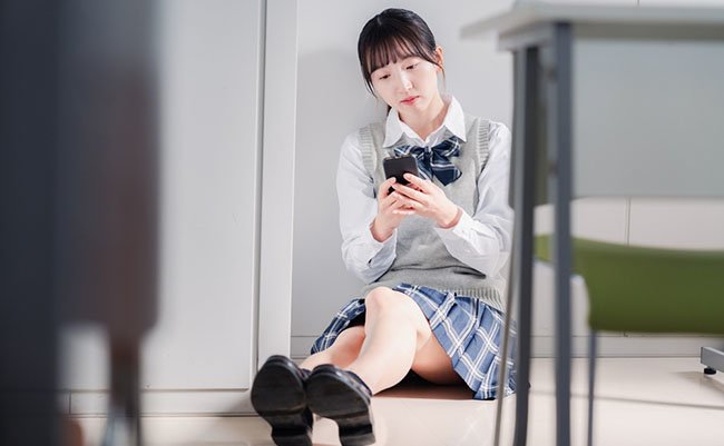 A high school girl who is depressed while looking at her phone