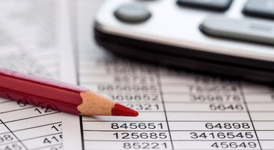 a calculator is on a balance sheet numbers are statistics. photo icon for sales, profits and costs.