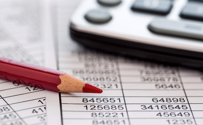 a calculator is on a balance sheet numbers are statistics. photo icon for sales, profits and costs.