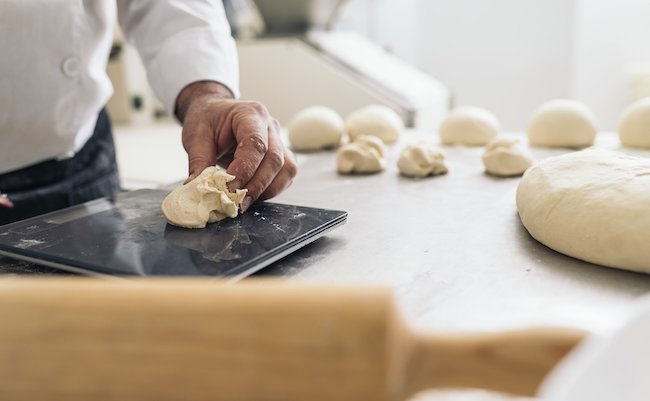 Baker kneading dough in a bakery. Bakery Concept.