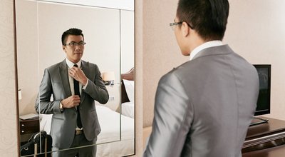 Young Asian businessman getting ready in front of big mirror
