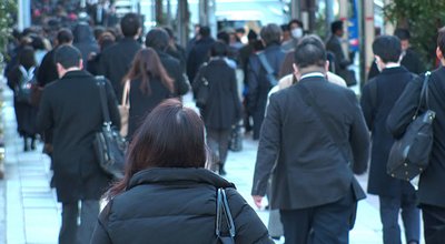 TOKYO, JAPAN - MAR 2020 : Back shot of unidentified crowd of people walking down the street in busy rush hour. Many commuters going to work. Japanese business man and woman, job and lifestyle concept.