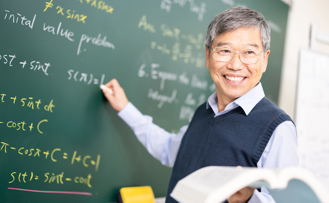 asian senior male calculus professor is writing on blackboard in the classroom at college