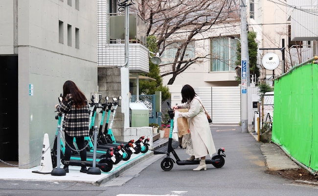 TOKYO, JAPAN - March 24th, 2022: People renting Luup rental e-scooters in Tokyo's Aoyama area in Shibuya Ward.