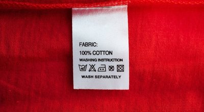 White laundry care washing instructions clothes label on red cotton shirt