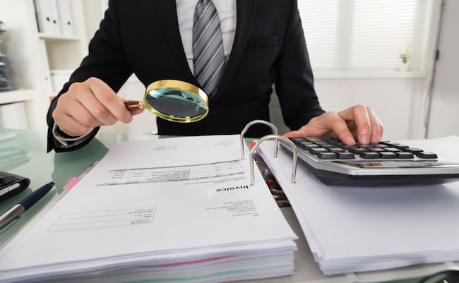 Photo Of Businessman Analyzing Bills With Magnifying Glass