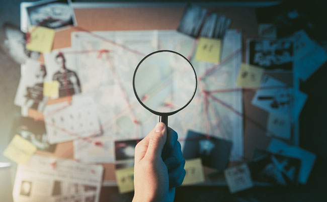 Detective,Hand,Holding,A,Magnifying,Glass,In,Front,Of,A