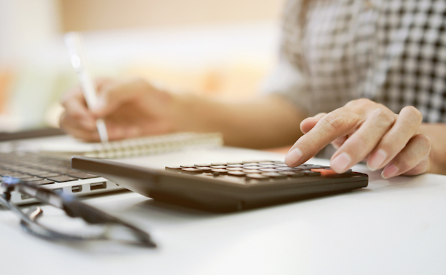 senior woman hand press for calculating on calculator and writing on notebook about welfare and money monthly after retirement at the table in home office and managing expense economic inflation