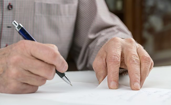 Elderly,Man,In,Grey,Shirt,Writes,Letter,On,Paper,Sheet