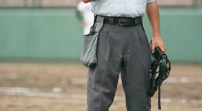 A ball umpire waits for the pitcher to practice pitching during a baseball game.