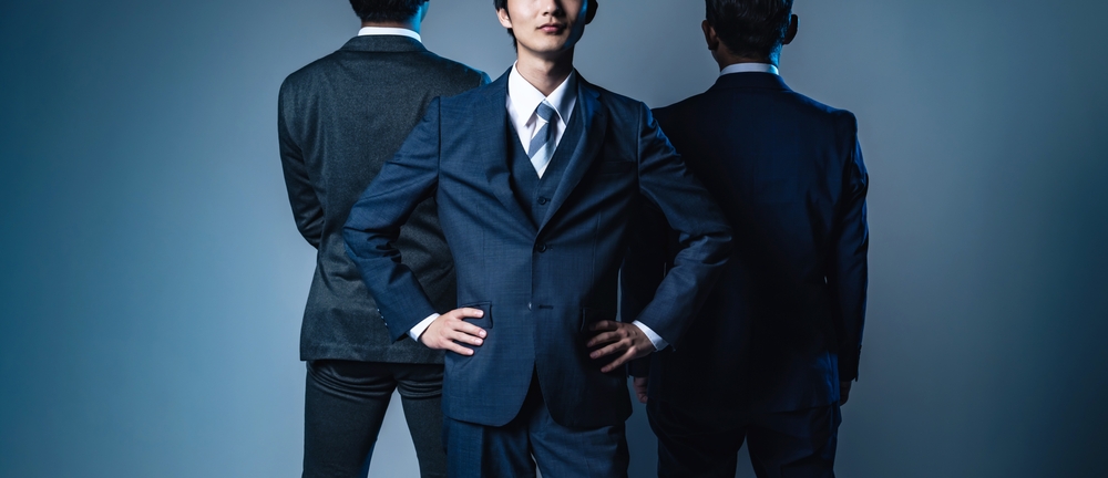 Young,Asian,Businessman,Posing,Between,Two,Bosses.