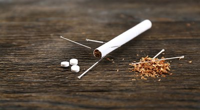 Acupuncture needles with cigarette on wooden background