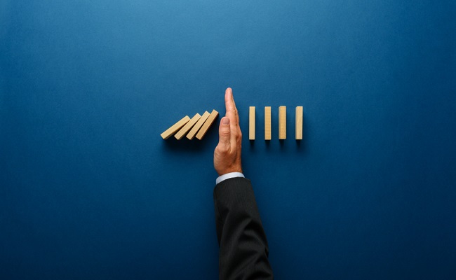 Top,View,Of,Businessman,Hand,Stopping,Falling,Dominos,In,A