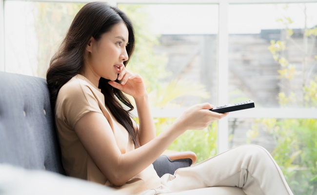 Beautiful,Woman,Watching,Tv,Program,On,Sofa,With,Remote,Control