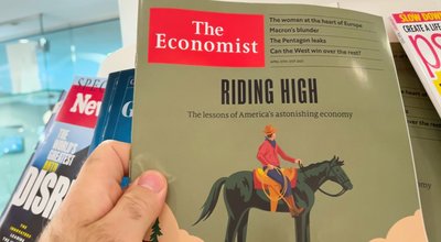 London, United Kingdom - 21 Apr 2023: A male hand holds the latest issue of The Economist, featuring an illustrated cover story on Americas economy. Journalism and mass media join forces to inform the