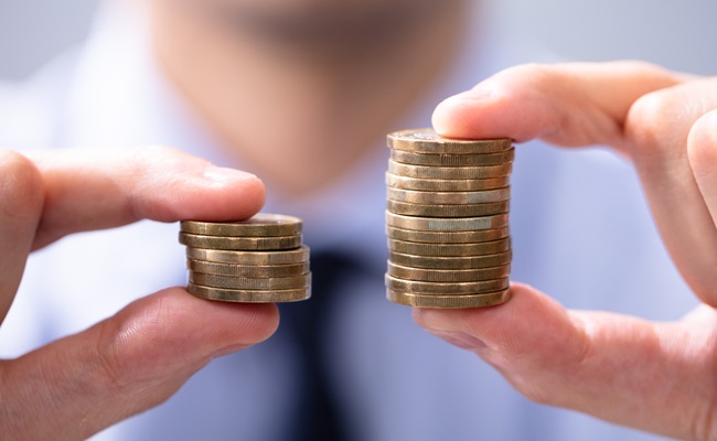 Man,Holding,Two,Coin,Stacks,To,Compare