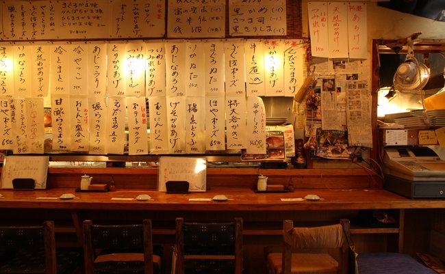 TOKYO, JAPAN - JULY 23, 2019: Very typical sushi restaurant in Tokyo with names of dishes written in japanese letters everywhere around the counter.