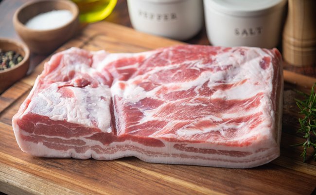 fresh pork belly block on wooden board