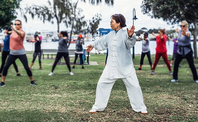 Mature,Chinese,Woman,Do,Tai,Chi,With,Blirred,Group,Of