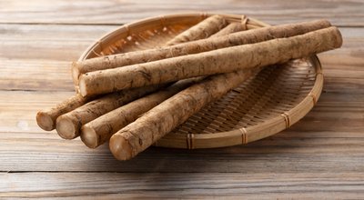 Burdock in a bamboo colander placed in the background of a wooden board
