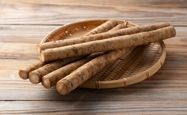 Burdock in a bamboo colander placed in the background of a wooden board