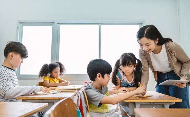 Pupil,Boy,Hi,Five,With,Asian,Teacher,In,Classroom,At