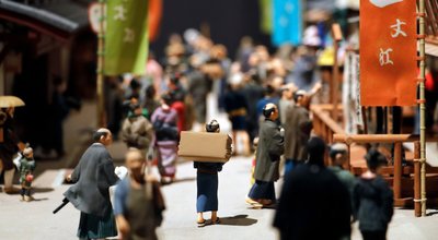A diorama depicting a Japanese merchant walking through a crowd in a busy street