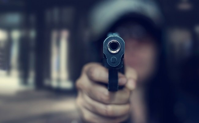 Woman,Pointing,A,Gun,At,The,Target,On,Dark,Background,
