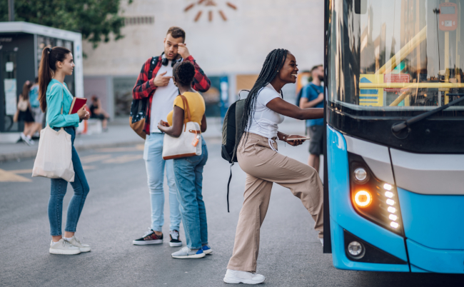 Multiracial,Passengers,Waiting,At,A,Bus,Stop,And,Talking,Cheerfully.