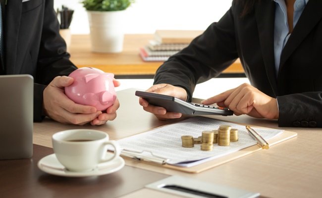 Businessperson's,Hand,With,Pink,Piggy,Bank,With,Thermostat,And,Coins