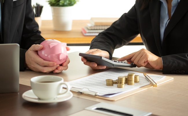 Businessperson’s,Hand,With,Pink,Piggy,Bank,With,Thermostat,And,Coins
