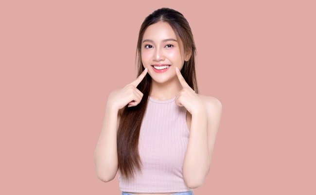 Beautiful,Young,Asian,Woman,Pointing,Finger,To,Her,Teeth,On