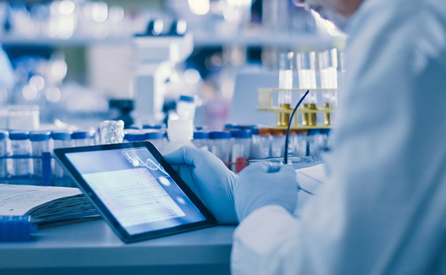 Senior Male Research Scientist is Using a Tablet Computer in a Modern High-Tech Laboratory. Genetics and Pharmaceutical Studies and Researches.