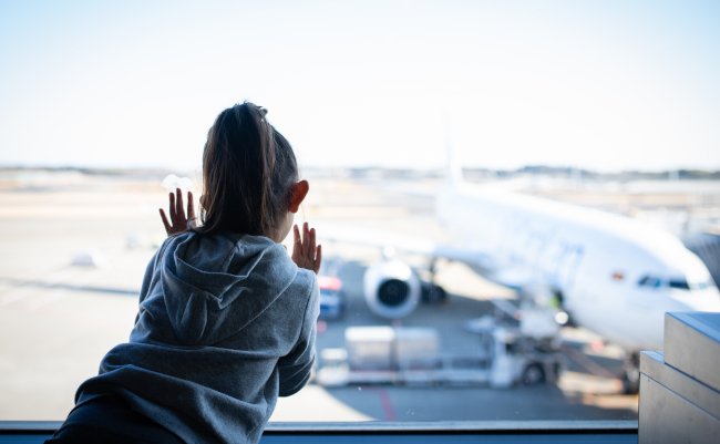 Child,Looking,At,Airplane,From,Airport,Window