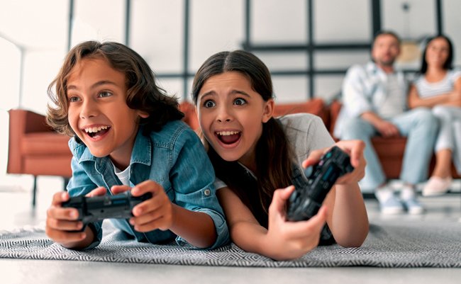 Beautiful mother and handsome father with their daughter and son spending time together at home. Children are playing video games. Happy family concept.