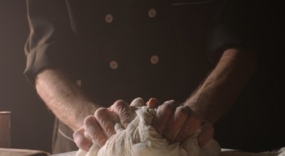 Hands,Of,Senior,Experienced,Chef,Kneading,Floured,Dough,At,Bakery,