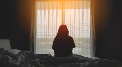 Silhouette,Of,Woman,Sitting,On,The,Bed,Beside,The,Windows