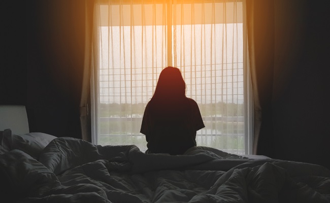 Silhouette,Of,Woman,Sitting,On,The,Bed,Beside,The,Windows