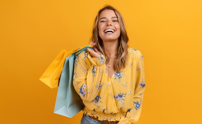 Beautiful,Attractive,Smiling,Woman,In,Yellow,Shirt,And,Jeans,Holding