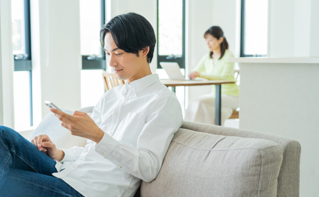 Japanese,Man,Looking,At,Mobile,Phone,At,Home
