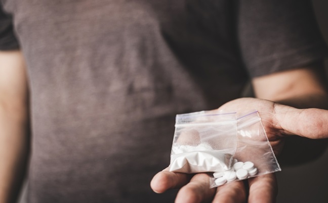 Man’s,Hand,Holds,Two,Transparent,Plastic,Packets,With,Cocaine,Powder