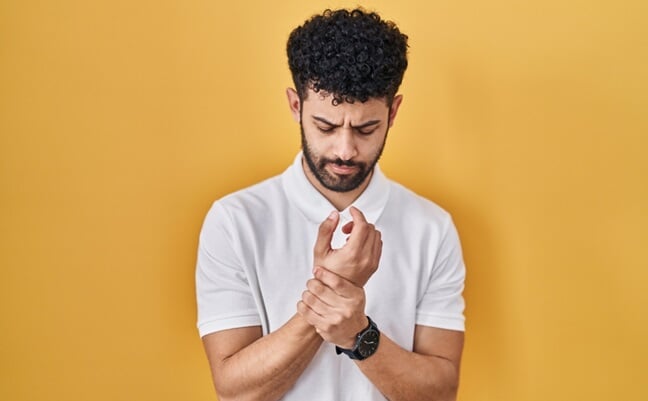 Arab,Man,Standing,Over,Yellow,Background,Suffering,Pain,On,Hands