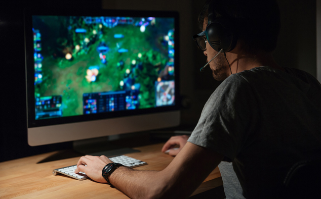 Back,View,Of,Concentrated,Young,Gamer,In,Headphones,And,Glasses
