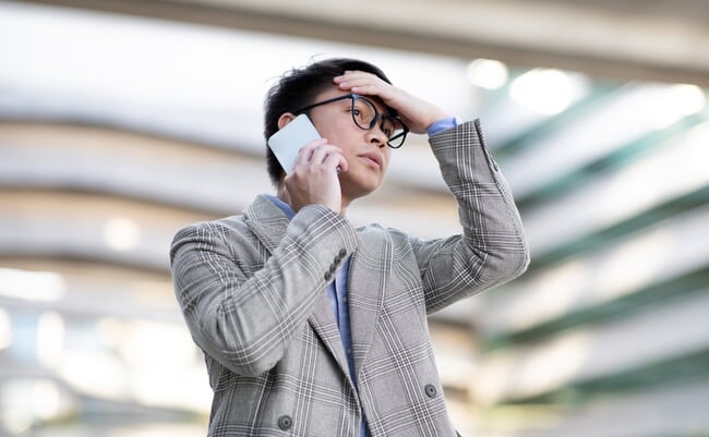 Young,Asian,Businessman,Frowns,At,His,Phone,During,Challenging,Call,
