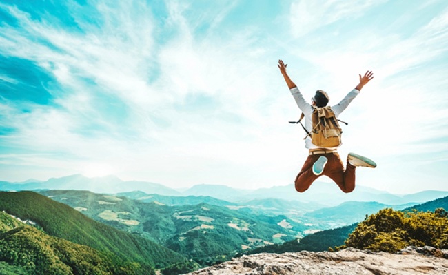 Happy,Man,With,Backpack,Jumping,On,Top,Of,The,Mountain