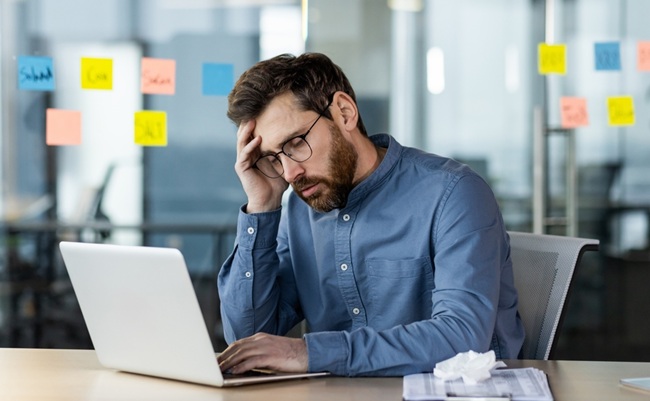 Stressed,Office,Worker,Sitting,At,Desk,With,Laptop,Feeling,Burnout.