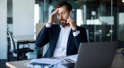 Concerned,Male,Entrepreneur,Talking,On,Cellphone,And,Touching,Head,In