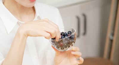 Asian,Woman,Eating,Blueberries,In,Dining,Room,,No,Face