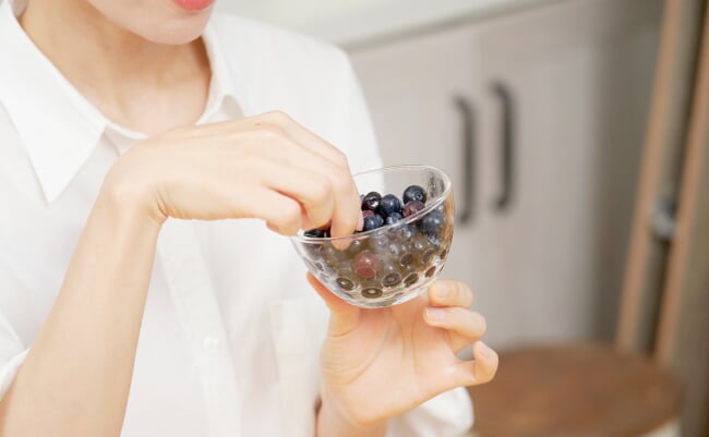 Asian,Woman,Eating,Blueberries,In,Dining,Room,,No,Face