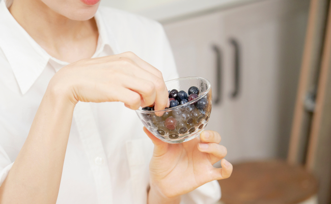 Asian,Woman,Eating,Blueberries,In,Dining,Room,,No,Face